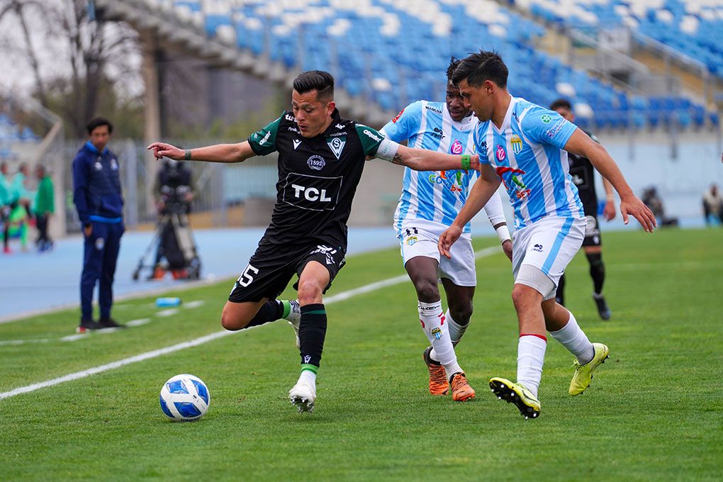 El delantero Carlos Muñoz de Wanderers aguantando la marca de un defensor de Magallanes.