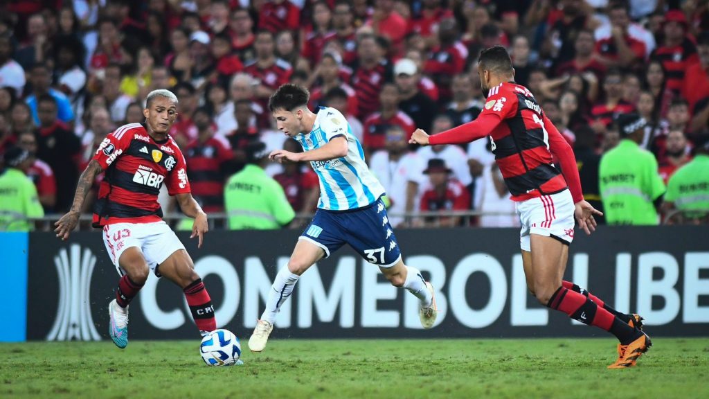 Futbolistas de Flamengo yendo a buscar el balón ante un jugador de Racing Club.