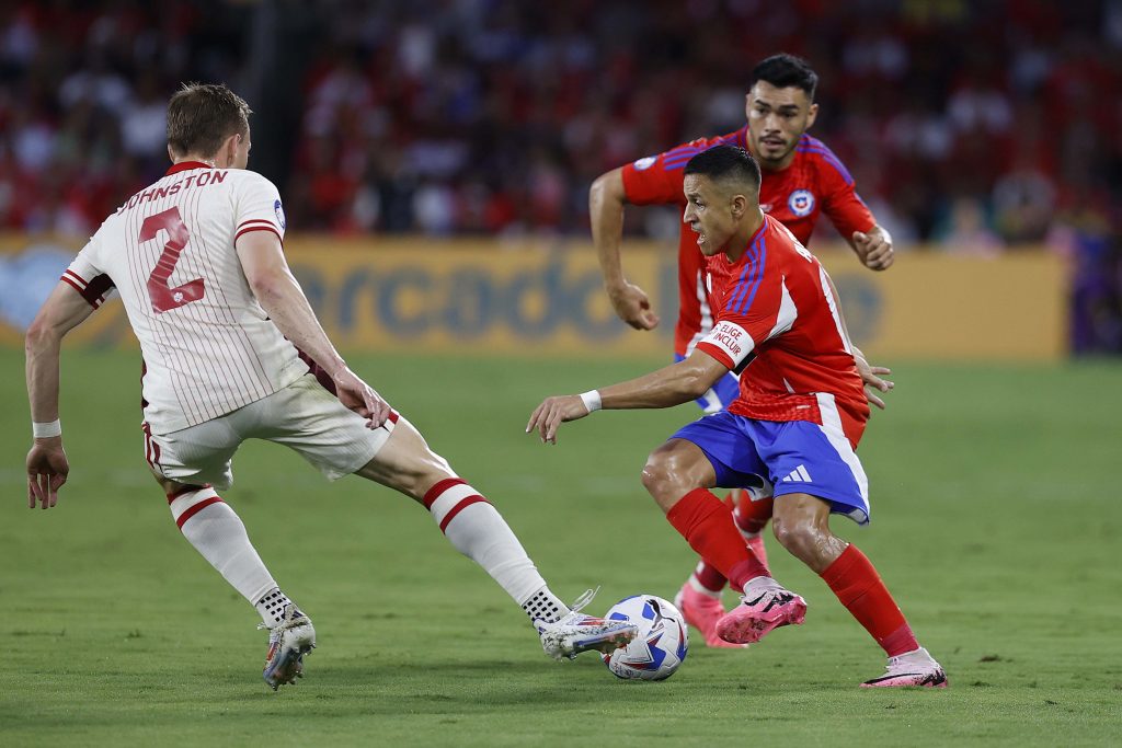 El delantero de Chile, Alexis Sánchez corriendo con el balón ante la marca de Johnston de Canadá.